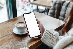 Hände halten Telefon mit Weiß Attrappe, Lehrmodell, Simulation Bildschirm gegen Kaffee Tabelle Hintergrund foto