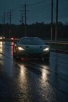ein Sport Auto Fahren Nieder ein nass Straße beim Nacht foto