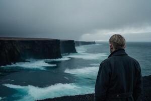 Mann Stehen auf das Kante von das Cliff suchen beim das Ozean foto