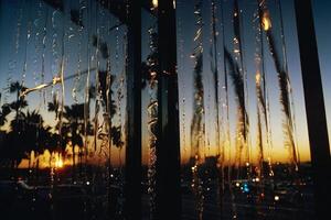 ein Aussicht von das Sonnenuntergang durch ein Fenster mit Wasser Tropfen foto