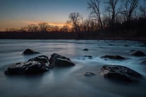 ai generiert Fluss fließt Über Felsen beim Sonnenuntergang foto