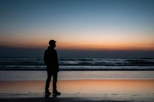 Silhouette von ein Mann Stehen auf oben von ein Hügel beim Sonnenuntergang foto