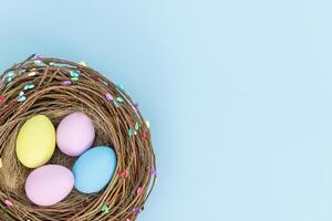 Ostern Farbe Eier im Vogel Nest auf Blau Hintergrund - - oben Aussicht foto