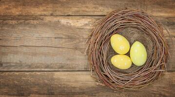 drei Gelb Ostern Eier im Vogel Nest auf hölzern Hintergrund - - oben Aussicht foto