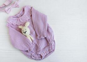 Rosa Bodysuit mit Spielzeug gestrickt Spielzeug und Stirnband. foto