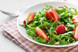 frisch Erdbeere Rucola Salat mit Kiefer Nüsse serviert auf ein hell Tag foto