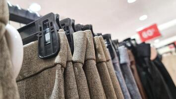 Reihen von Hose im ein Kleidung Geschäft hängend ordentlich auf Kleiderbügel. foto