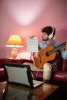 Junge Lehren Fernbedienung Musik- Gitarre Lektion durch Computer Streaming Anruf foto