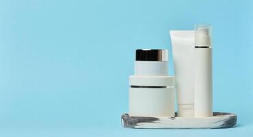 Weiß Plastik Rohre, Gläser, und Behälter zum kosmetisch Produkte auf ein Blau Hintergrund foto