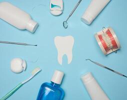 Mundwasser, Zahnpasta Rohr, Dental Zahnseide und medizinisch Spiegel auf ein Blau Hintergrund, Oral Hygiene. oben Aussicht foto