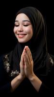 Süd-Ost asiatisch Frau tragen Schal ist beten und lächelnd auf schwarz Hintergrund foto