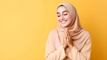 Arabisch Frau tragen Schal ist beten und lächelnd auf Gelb Hintergrund foto