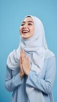 Süd-Ost asiatisch Frau tragen Schal ist beten und lächelnd auf Blau Hintergrund foto