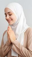 Arabisch Frau tragen Schal ist beten und lächelnd auf grau Hintergrund foto
