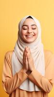 europäisch Frau tragen Schal ist beten und lächelnd auf Gelb Hintergrund foto