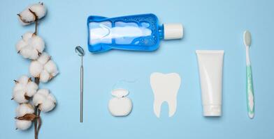 Mundwasser, Zahnpasta Rohr, Dental Zahnseide und medizinisch Spiegel auf ein Blau Hintergrund, Oral Hygiene foto