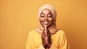 afrikanisch Frau tragen Schal ist beten und lächelnd auf Gelb Hintergrund foto