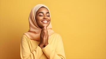 afrikanisch Frau tragen Schal ist beten und lächelnd auf Gelb Hintergrund foto