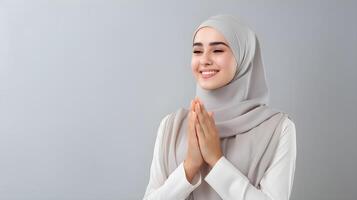 Arabisch Frau tragen Schal ist beten und lächelnd auf grau Hintergrund foto