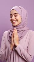 Arabisch Frau tragen Schal ist beten und lächelnd auf lila Hintergrund foto