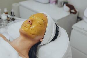 ein Mädchen beim ein Kosmetikerin tut kosmetisch Verfahren. Alginat Maske foto
