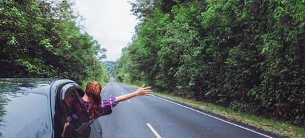 asiatische frauen reisen im urlaub entspannen. mit dem Parkplatz unterwegs. glücklich mit der Natur, ländlichen Wald. im Sommer. Frau, die ein Auto fährt, das glücklich reist. foto