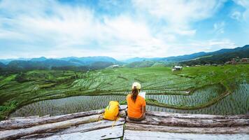 asiatisch Frau Reise Natur. Reise entspannen. Stehen lesen Buch das Balkon von das Erholungsort. Aussicht von das Feld auf das Berg im Sommer. Thailand foto