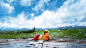 asiatisch Frau Reise Natur. Reise entspannen. Stehen lesen Buch das Balkon von das Erholungsort. Aussicht von das Feld auf das Berg im Sommer. Thailand foto