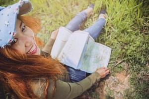 Frau reisen. asiatische frauen sehen karte reisen natur auf der wiese foto