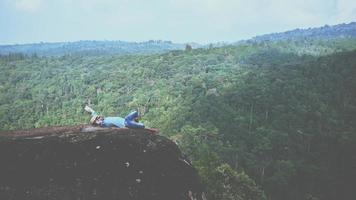 asiatische Mannreisen entspannen sich im Urlaub. schlafen entspannen lesen bücher auf felsigen klippen. auf dem Berg. in Thailand foto