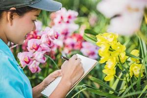 junge Frauen schreiben Hinweis unter Orchideengarten. bunte Orchideen, Orchideenblüte.