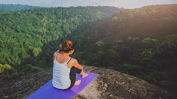 asiatische frauen entspannen sich im urlaub. spielen, wenn Yoga. auf der Bergfelsenklippe. Natur der Bergwälder in Thailand