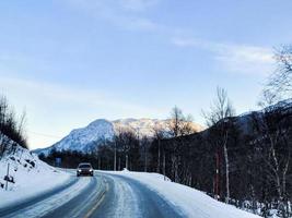 Fahren durch verschneite Straße und Landschaft, Norwegen. Auto vor. foto