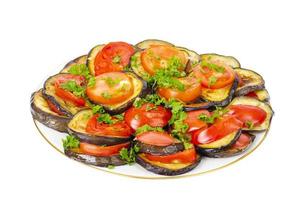 Auberginen-Vorspeise mit Tomaten auf Teller, weißer Hintergrund. Studiofoto foto