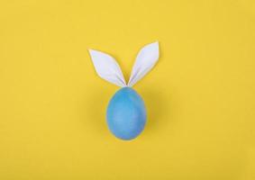 Ei mit Papierohren in Form eines Osterhasen. Frohe Ostern Konzeptkarte Poster Hintergrund foto