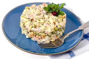 russischer Gemüsesalat mit Erbsen und Mayonnaise auf blauem Teller foto