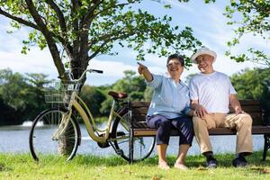 glücklich und gesund Paar asiatisch Sitzung Stuhl neben ein Fahrrad Familie und Freundschaft Lebensstil, Vergnügen von aktiv Senioren, und draussen Aktivität nach Ruhestand, Gesundheit Pflege Versicherung Konzept foto