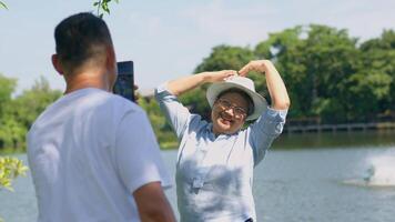 glücklich und gesund Paare asiatisch Foto und vlog Selfie zusammen zum Sozial Medien im Park auf Freizeit. Familie und Freundschaft Lebensstil, Vergnügen von aktiv Senioren, und draussen Aktivität nach Pensionierung