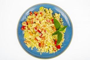 Vegetarischer Couscous-Pilaw mit Gemüse auf blauem Teller. Studiofoto foto