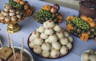Stapel von Gebäck im ein Tablett sind auf das Tabelle mit Essen und Obst zu Angebot zu das Verstorbene gemäß zu Buddhist Überzeugungen. foto