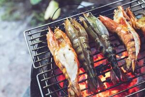 groß Garnelen sind platziert auf ein Eisen Bratpfanne und gegrillt Über ein heiß Kohle Herd. foto