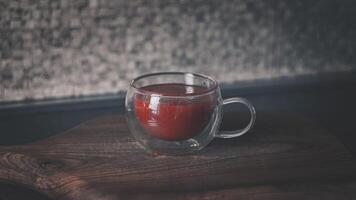 Glas Tasse mit Tomate Saft auf ein hölzern Schneiden Tafel foto