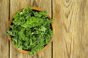 frische grüne Sabellica-Blätter auf Holzuntergrund, gesunde Bio-Lebensmittel.