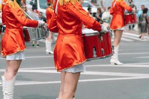 jung Mädchen Schlagzeuger im rot Jahrgang Uniform beim das Parade. Straße Performance von festlich März von Schlagzeuger Mädchen im rot Kostüme auf Stadt Straße foto