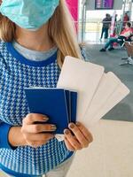 Frau im medizinisch Maske halten Pässe und Einsteigen Reisepass beim Flughafen foto