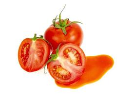 Klecks Tomatensaft und frische rote Tomaten auf weißem Hintergrund. foto