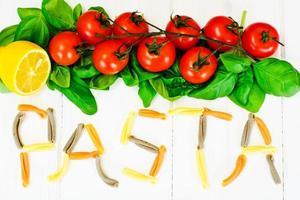 Basilikum, rote Kirschtomate mit Nudeln auf weißem holzigem Hintergrund foto