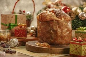 Panettone, Rosinen und kandierte Fruchtwürfel auf Holzbrett mit Weihnachtsschmuck foto