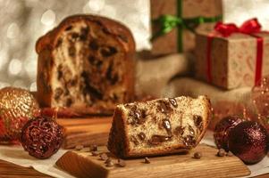 Scheibe Schokoladenpanettone auf Holzbrett mit Weihnachtsschmuck foto