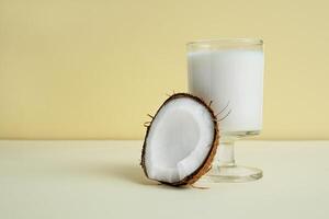 ein Stück von Kokosnuss in der Nähe von ein Glas von vegan Kokosnuss Milch foto